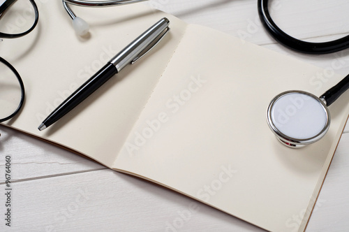 Open notebook with stethoscope, pen and stylish sunglasses