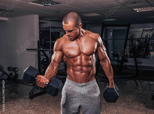 Handsome muscular man exercise with weights.
