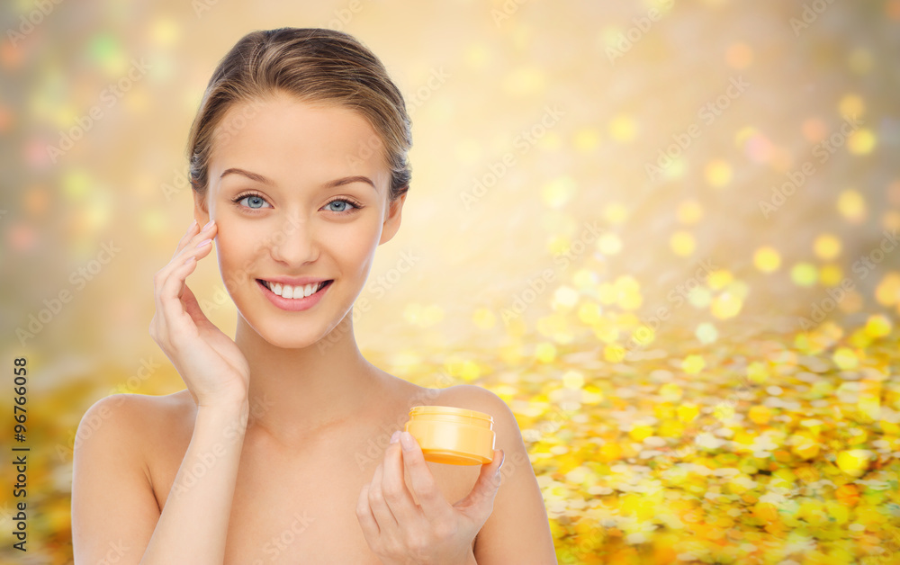 happy young woman applying cream to her face happy young woman applying cream to her face