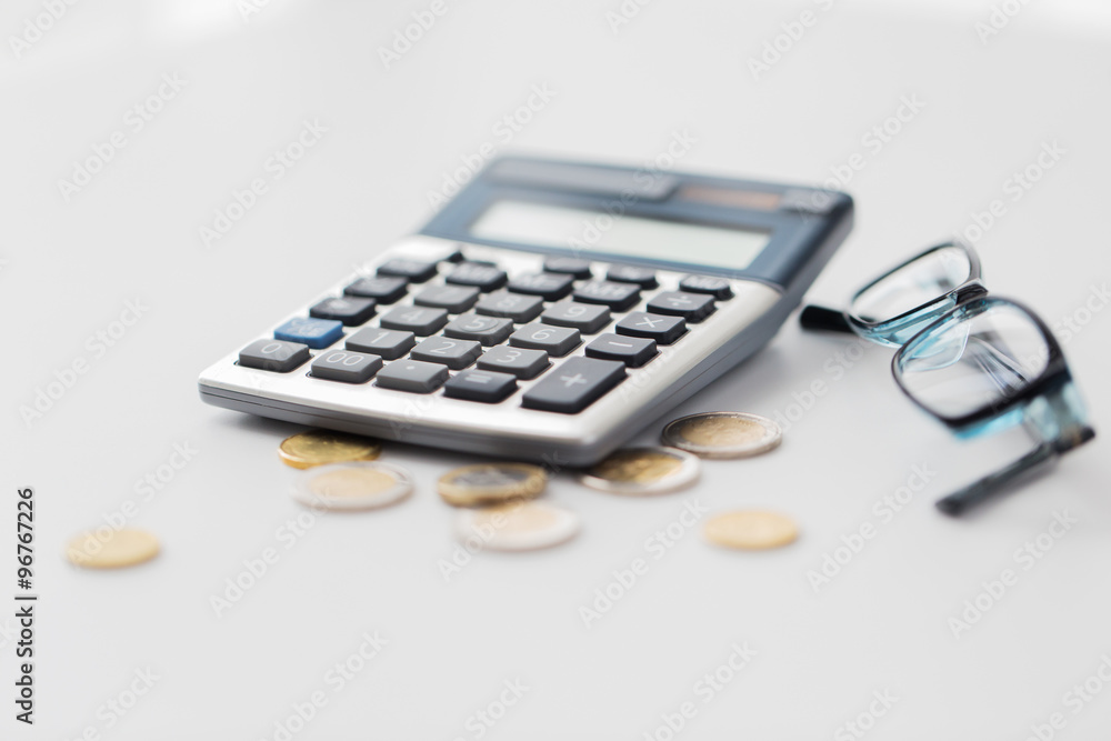 calculator, eyeglasses and coins on office table calculator, eyeglasses and coins on office table