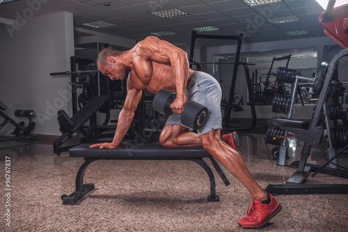 Obraz na plátně Muscular strong man exercise with weights in the gym.