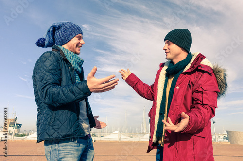 Men models wearing winter clothes using gesturing in friendly discussion - Best male friends are hugging - Trendy students having fun outdoor in sunny day - Concept of friendship happiness and youth 