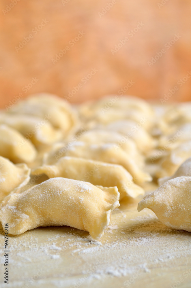 Vareniki (dumplings) with potatoes. Uncooked on the wooden desk. Close-up, shallow depth of field.