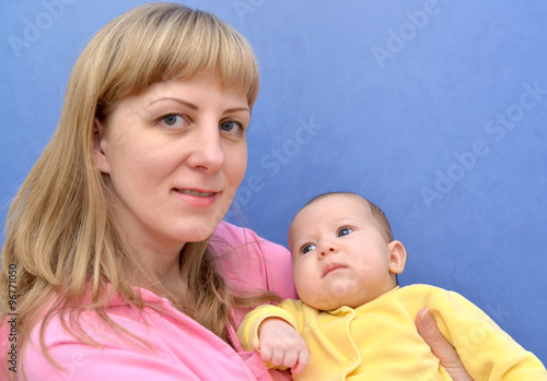 Family portrait of the young woman with the baby on a blue backg