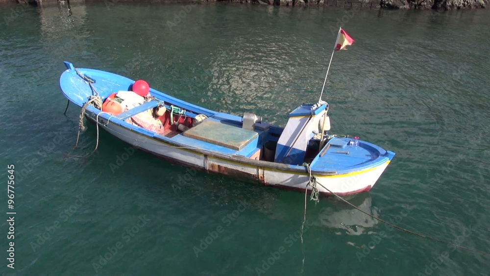 Small white and blue boat floating on water in sea Small white and blue boat floating on water in sea