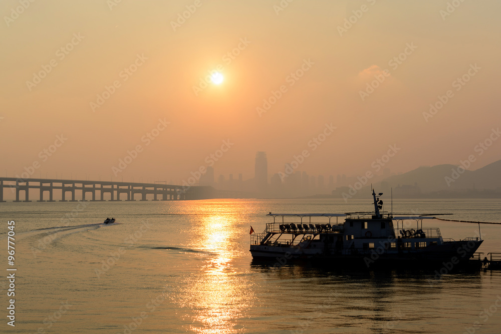Silhouette of boat with city at twilight in dalian, China