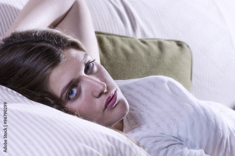 Obraz premium Portrait of a teenage girl, lying on a couch, looking at camera