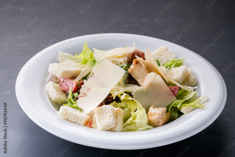 Caesar salad with chicken and greens on wooden table Caesar salad with chicken and greens on wooden table