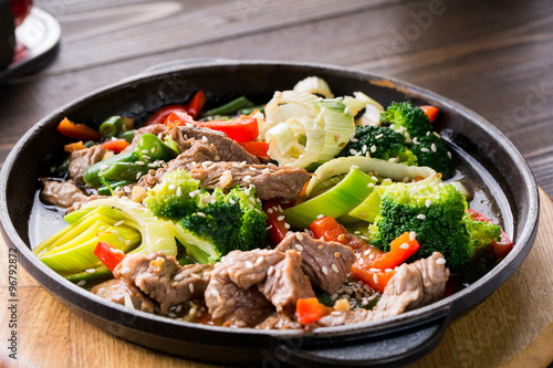 beef stew with vegetables in a frying pan over dark background