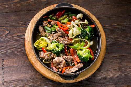 beef stew with vegetables in a frying pan over dark background