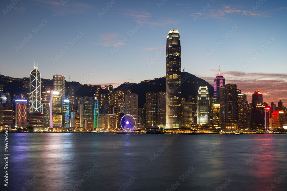 Obraz premium Scenic view of Hong Kong Island's skyline at evening over Victoria Harbor with lit urban skyscrapers in Hong Kong, China.