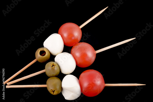 toothpick with olive, mozzarella and tomato  on black background italian flag food