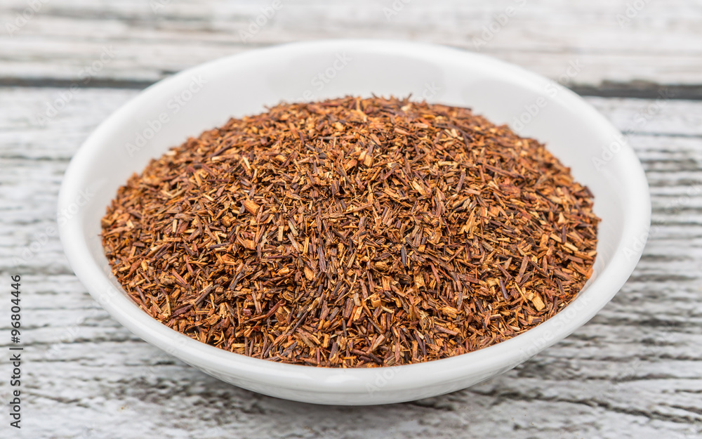 Dried South African rooibos herbal tea in white bowl over wooden background Dried South African rooibos herbal tea in white bowl over wooden background