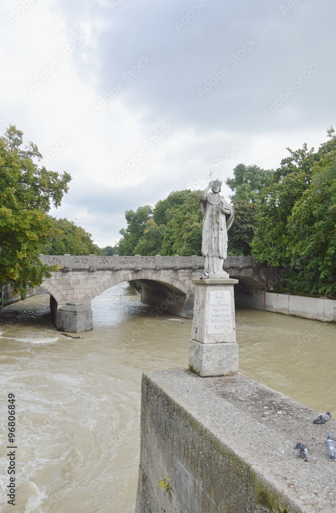 Памятник на мосту Praterwehrbrucke через реку Изар после дождей в пасмурную погоду (Мюнхен, Германия)