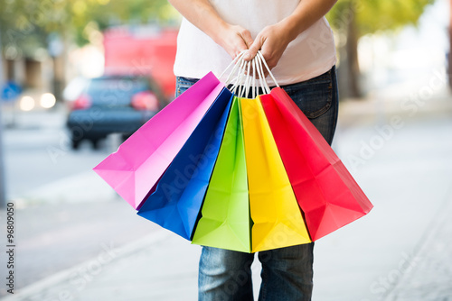Midsection Of Woman Holding Colorful Shopping Bags