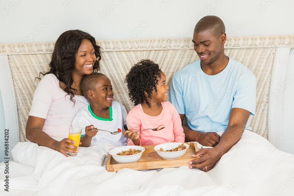 Happy family having breakfast in bed together 