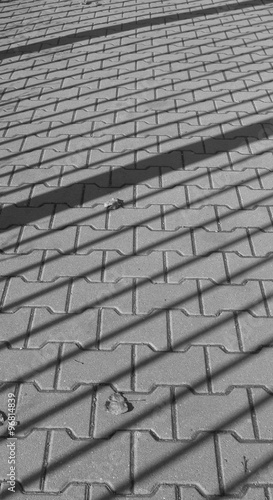 black and white photo of shadow of bannister on the sidewalk