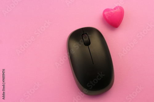 Wireless computer mouse and pink heart - love technology concept - on pink background