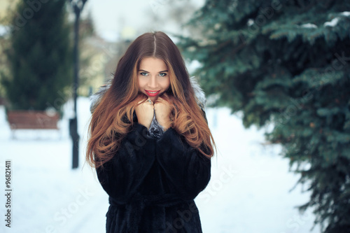 beautiful smiling girl on background of snowy trees. Winter portrait. coat with a hood photo