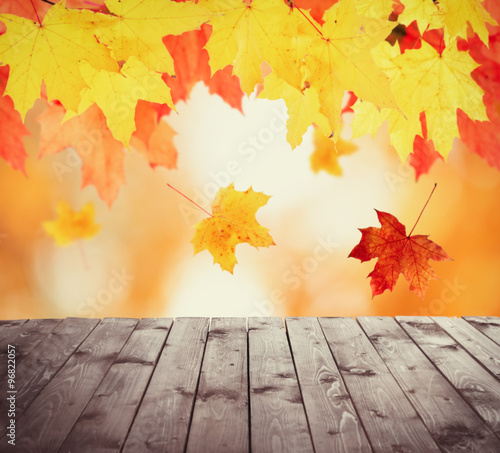 Autumnal leaves with bokeh and wooden floor. Beautiful natural autumnal background