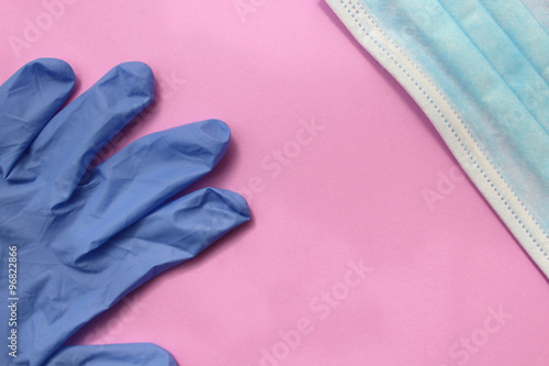 Sterile surgical glove and protective mask on pink background © greenview
