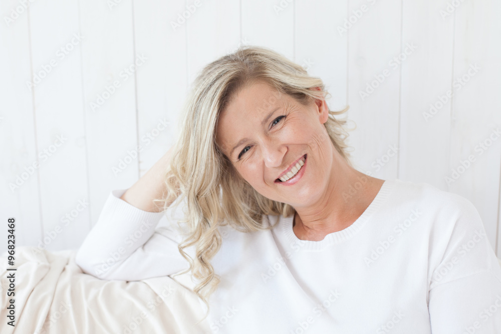beautiful adult woman with blond hair, smiling, happy drinking coffee, tea.He is sitting on the sofa with a cup in hand.