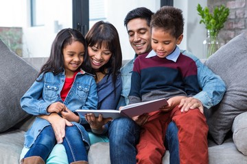 Happy young family reading a book together