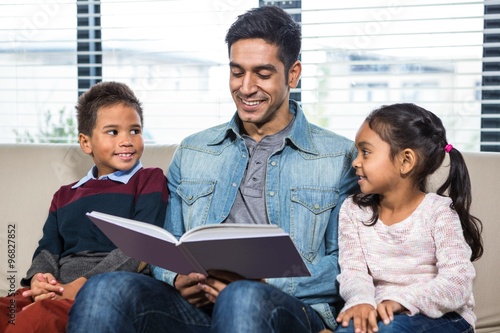 Happy father reading a book for his children © WavebreakmediaMicro