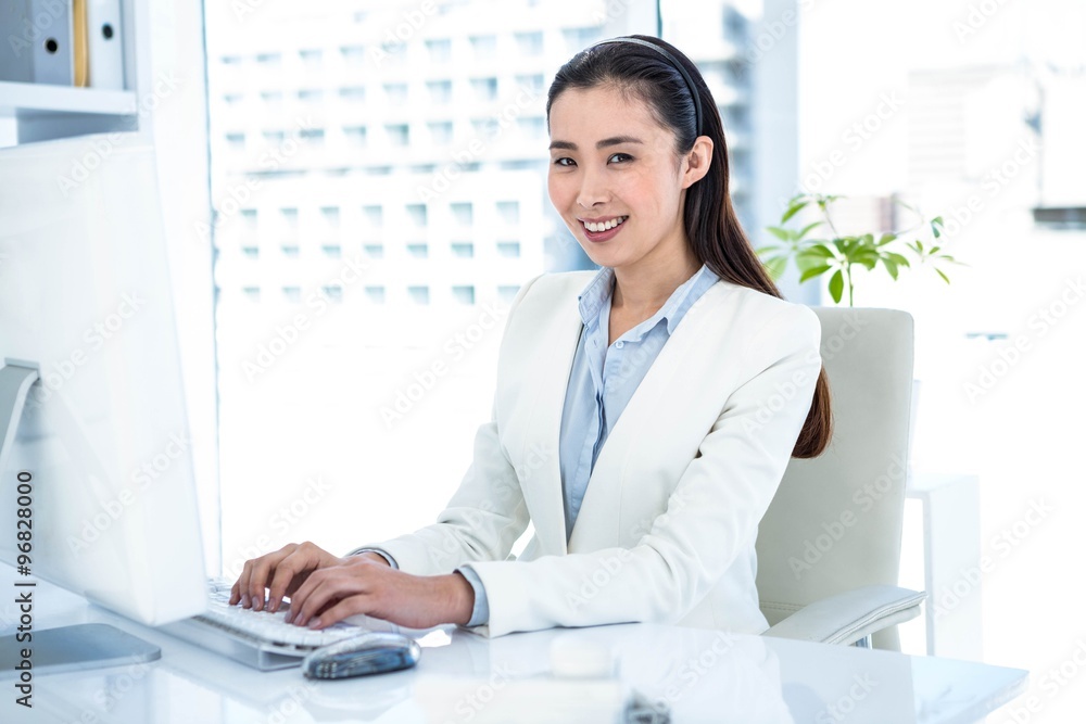 Smiling businesswoman typing on keyboard Smiling businesswoman typing on keyboard