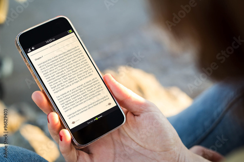 woman sitting in the street holding her smartphone with ebook photo