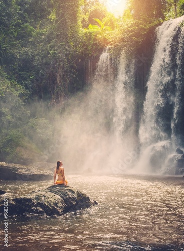 Beautiful woman sitting near waterfall enjoying the sun, Phnom Koulen at Siem Reap, Cambodia