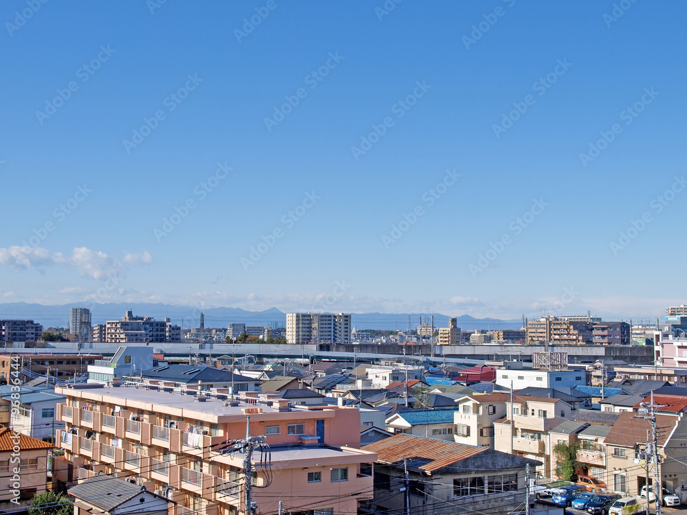 Houses, mansions and a railway bridge in front of japanese mountains