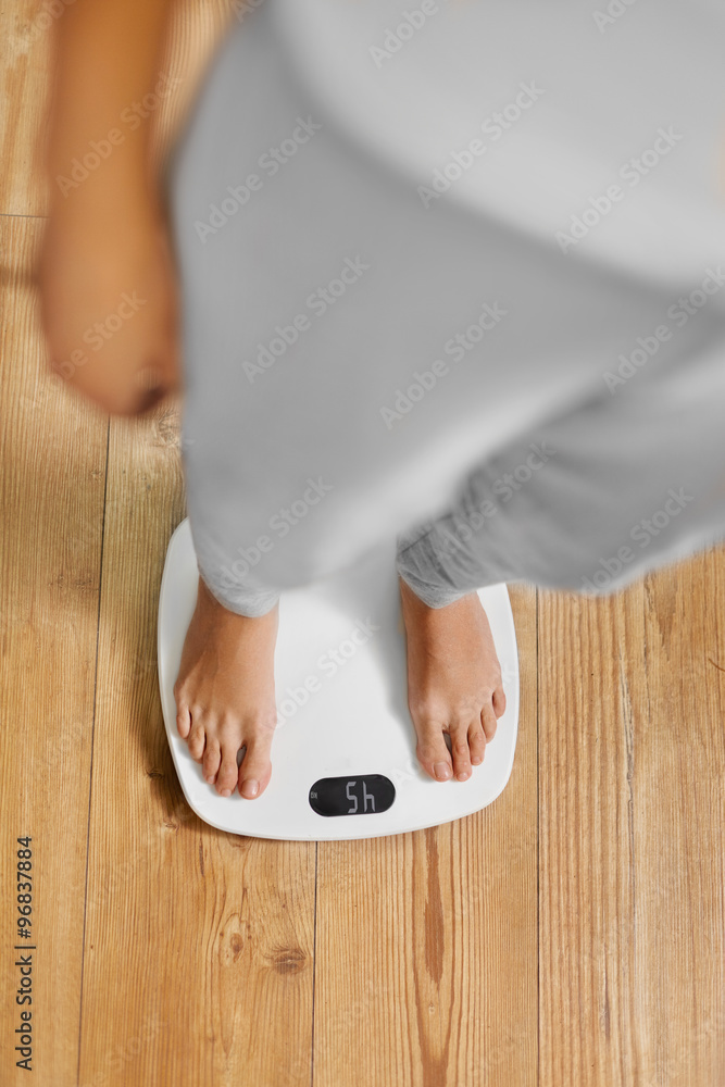 Diet. Top View Of Female Bare Feet Standing On A Scale. Caucasian Young  Woman Measuring Body Weight On Weighing Scale At Home. Weight Loss.  Dieting; Exercising. Healthy Eating; Lifestyle. Stock Photo