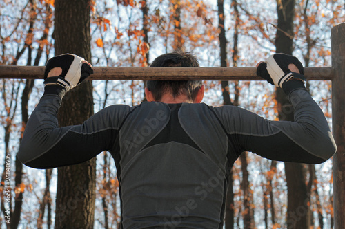 Strong muscular man workout outdoor on cold fall winter day. Man Doing Pull Ups Chin-Ups. Cold weather training, no excuse, sport, fitness, active lifestyle concept