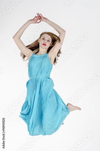 A slender girl with long hair dancing in a long summer dress 