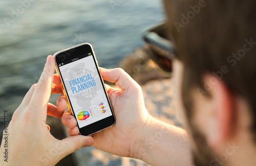 Man using his mobile phone on the coast with financial planning