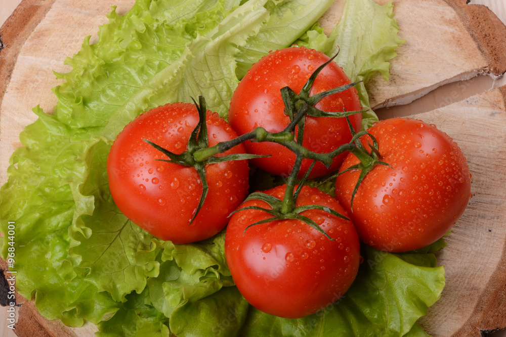 bunch of tomatoes and green salad on wooden coaster bunch of tomatoes and green salad on wooden coaster