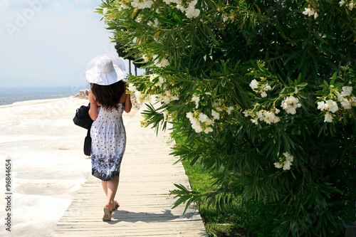Girl in a white hat and white dress goes. © photo_mts
