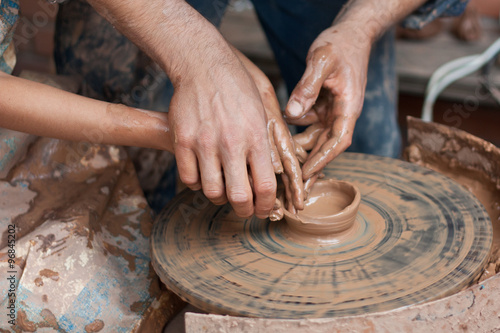 Potter teaches to sculpt in clay pot on a turning pottery wheel
