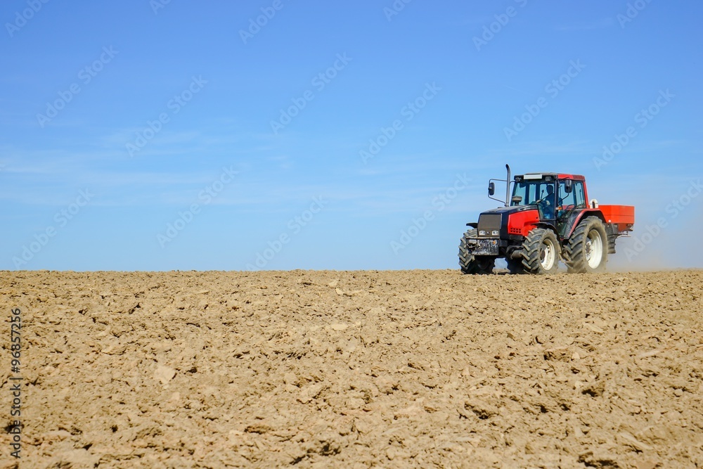Fototapeta premium Dünger streuen im Frühjahr auf ein gepflügtes Feld