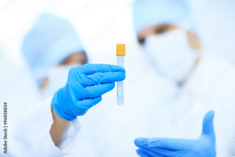 Two chemists are analyzing a liquid mixture in a test tube. Two chemists are analyzing a liquid mixture in a test tube.