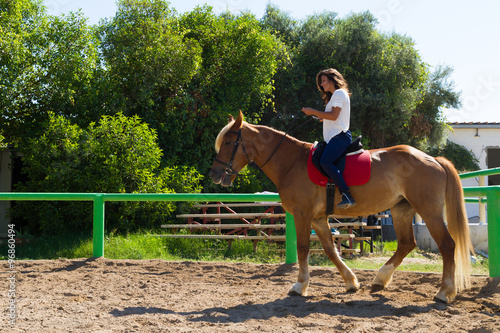 Young brunette on a brown-blond horse in the riding club
