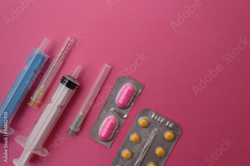 Syringe, needle, ampule and pills on pink background - medicine concept
