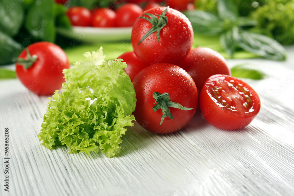 Cherry tomatoes with basil and lettuce on wooden table close up Cherry tomatoes with basil and lettuce on wooden table close up