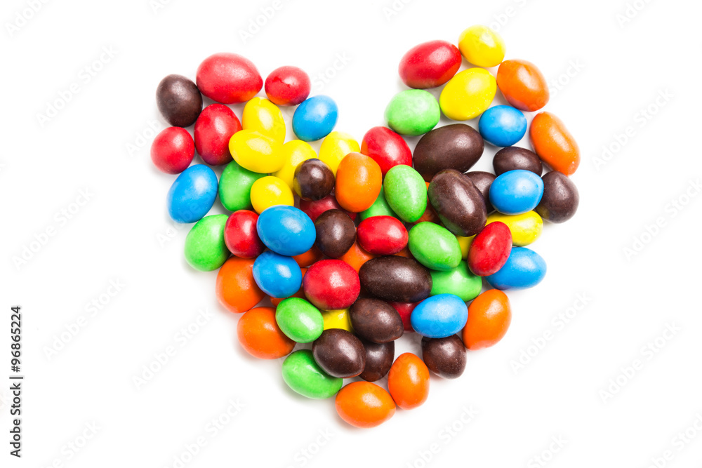 Heart shape with colorful milk chocolate candies on white backgr Heart shape with colorful milk chocolate candies on white backgr