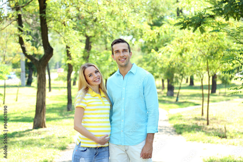 Young pregnant woman with husband walking in park Young pregnant woman with husband walking in park