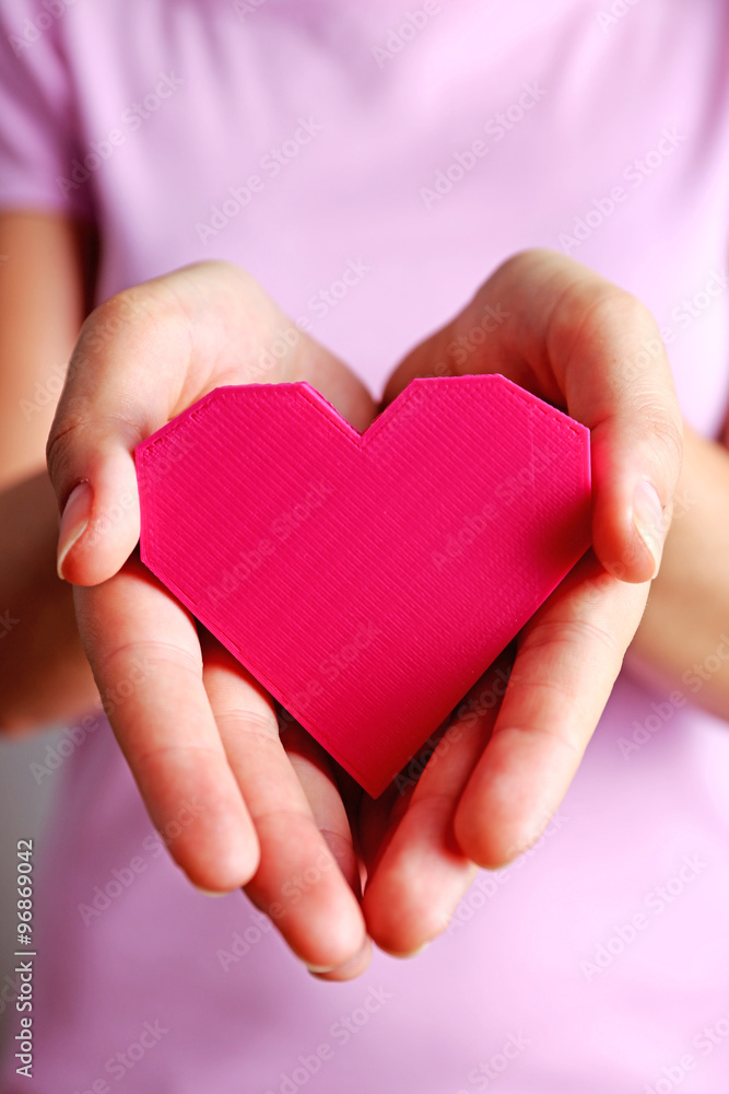 Closeup of plastic puzzle heart in female hands