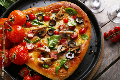Decorated pizza with vegetables on pan on wooden background