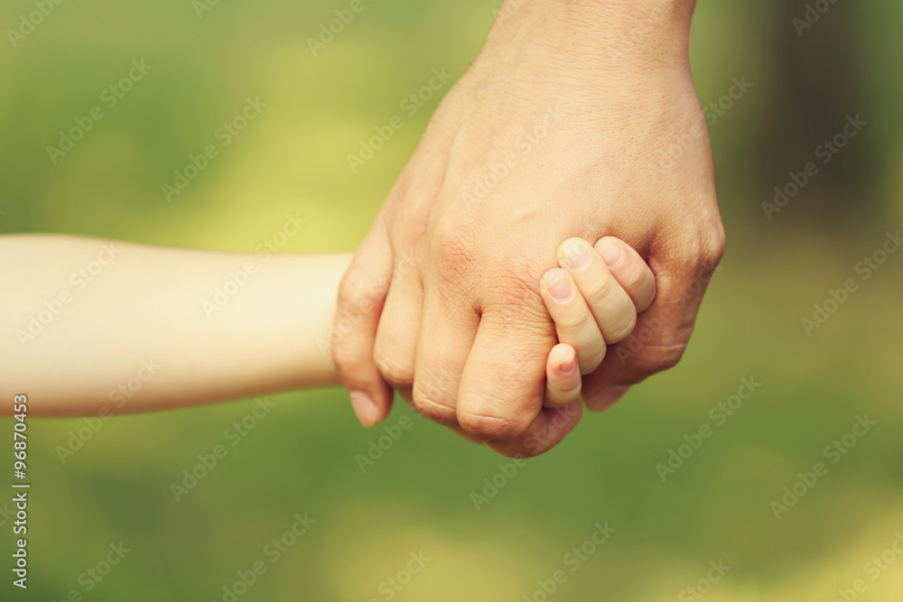 Father's hand lead his child daughter outdoors on green defocused background, trust family concept Father's hand lead his child daughter outdoors on green defocused background, trust family concept