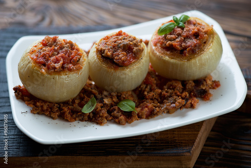 Baked onions stuffed with minced meat on a plate, close-up
